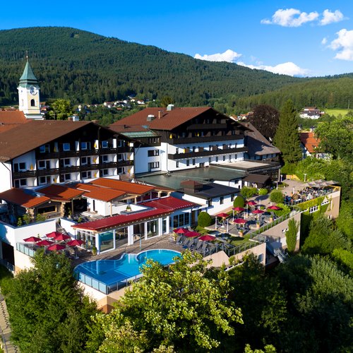Hotel Hofbräuhaus: freie Stellen Außenansicht des Wellnesshotels Hofbräuhaus in Bodenmais – Panoramablick auf Hotel, Außenpool, Saunen und Bayerischen Wald bei Sonnenschein