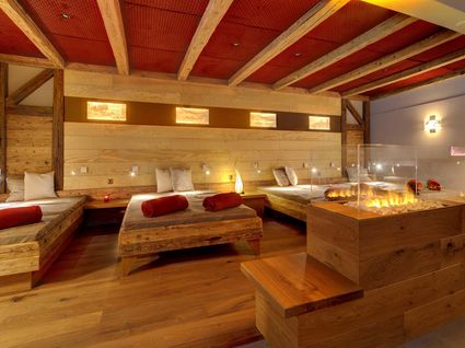 Herrliche Tageswellness in Bodenmais Moderner Ruheraum mit Holzliegen, Kaminfeuer und warmem Licht im Wellnesshotel Hofbräuhaus Bodenmais