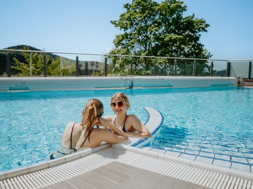 Urlaub mit Sauna: Ein Hotel in Bayern lädt ein. Zwei Frauen genießen den beheizten Außenpool mit Panoramablick im Wellnesshotel Hofbräuhaus Bodenmais