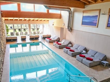 Herrliche Tageswellness in Bodenmais Großes Hallenbad mit Tageslicht und Relaxliegen im Wellnesshotel Hofbräuhaus Bodenmais – moderner Poolbereich für Gäste