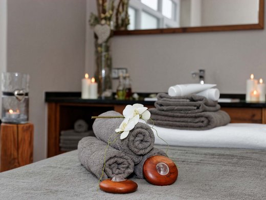 Das Hotel Hofbräuhaus in Bodenmais Massageraum mit gerollten Handtüchern, Orchidee und Kerzen – entspannende Atmosphäre im Wellnesshotel Hofbräuhaus Bodenmais