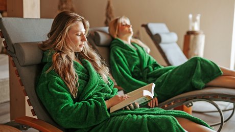 Entspannung im Bayerischen Wald: im Wellnesshotel Hofbräuhaus Zwei Frauen entspannen im Ruheraum auf Liegen im Wellnesshotel Hofbräuhaus Bodenmais – Erholung und Lesegenuss im Bademantel