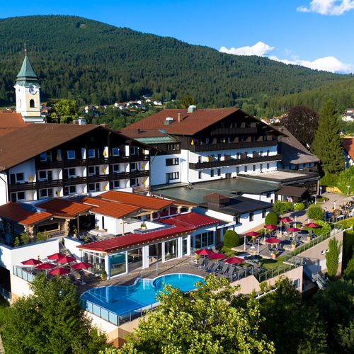 Hotel Hofbräuhaus: freie Stellen Außenansicht des Wellnesshotels Hofbräuhaus in Bodenmais – Panoramablick auf Hotel, Außenpool, Saunen und Bayerischen Wald bei Sonnenschein