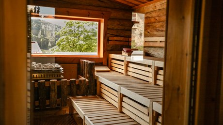 Sauna mit FKK: Urlaub im Bayerischen Wald Blick in die Kelosauna aus echtem Keloholz mit Panoramafenster und Ausblick auf die Natur im Wellnesshotel Hofbräuhaus Bodenmais