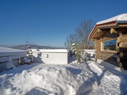 The best things to do around Bodenmais Verschneite Terrasse mit Blick auf eine winterliche Berglandschaft, rechts eine original Keloholz-Sauna, links Schneefiguren auf einer Mauer - im Wellnesshotel Hofbräuhaus in Bodenmais.