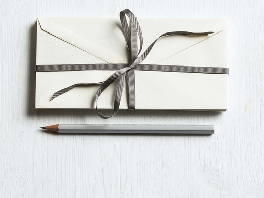 Enjoy an incredible day spa in Bodenmais Bleistift und Kuvert mit Schleife auf heller Oberfläche – stilvolle Geschenkidee oder Einladung, minimalistisch arrangiert