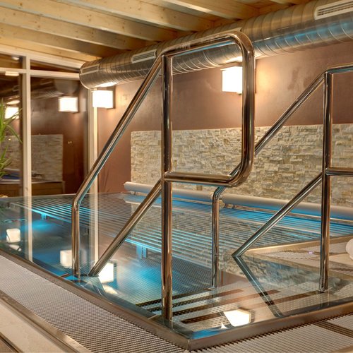 Häufige Fragen zum Wellnesshotel Hofbräuhaus in Bodenmais Panorama-Warmsprudelbecken im Innenbereich mit Kerzen und moderner Holzdecke im Wellnesshotel Hofbräuhaus Bodenmais