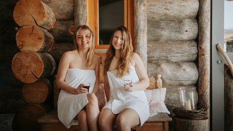 Sauna mit FKK: Urlaub im Bayerischen Wald Zwei Frauen entspannen nach der Sauna auf einer Holzbank im FKK-Bereich des Wellnesshotels Hofbräuhaus, Bodenmais, Bayerischer Wald